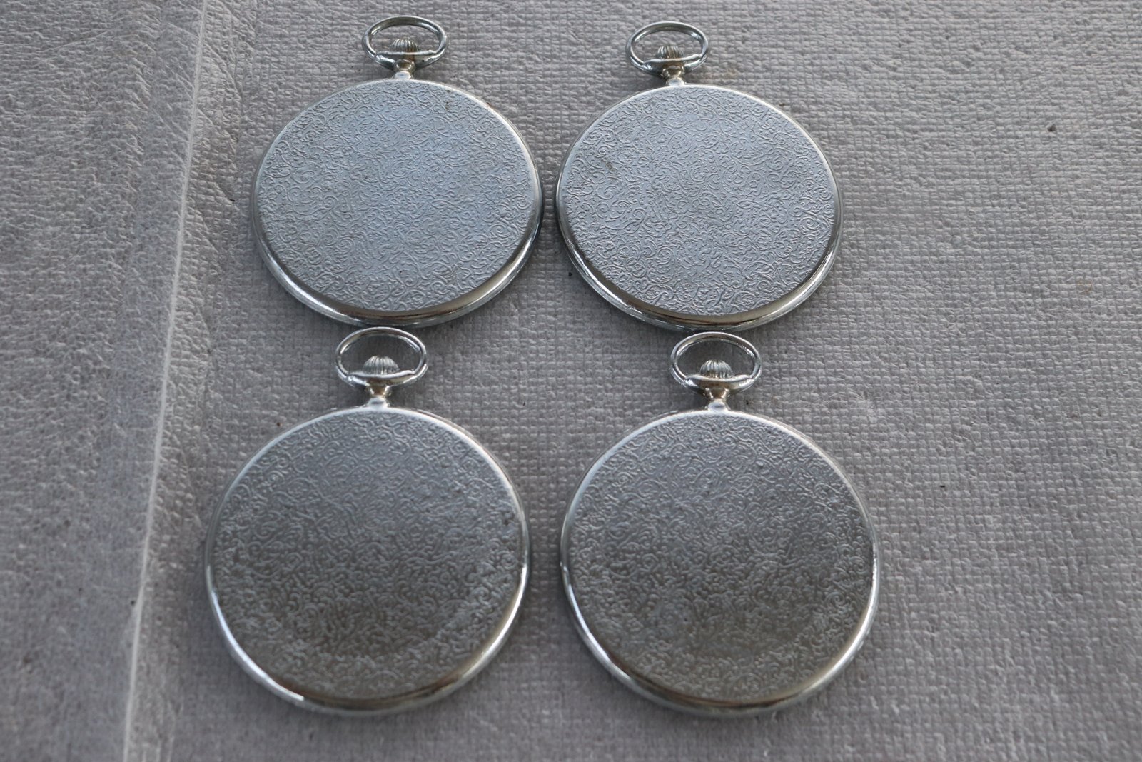 Backs of the four pocket-watch style metal coasters showing patterned finish (Lot 220)